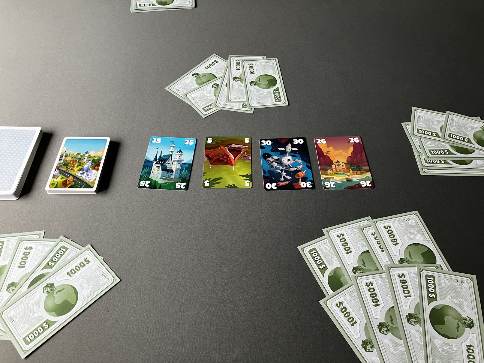 Es liegen 4 Immobilienkarten auf dem Tisch - 4 Gebote sind bereits platziert.