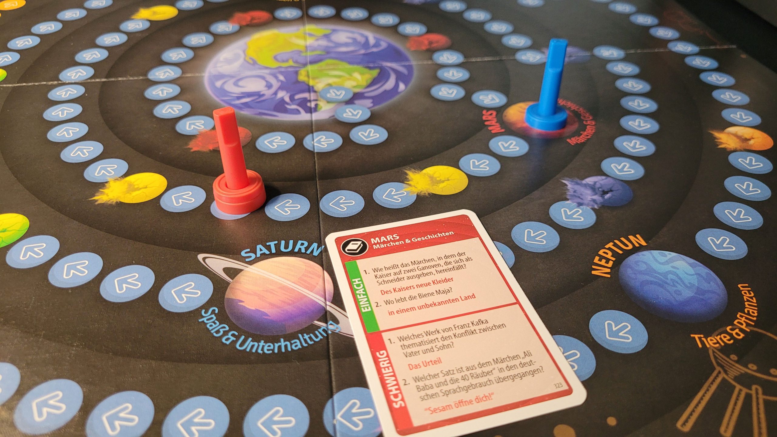 Zwei Figuren auf dem Spielplan eine Fragekarte