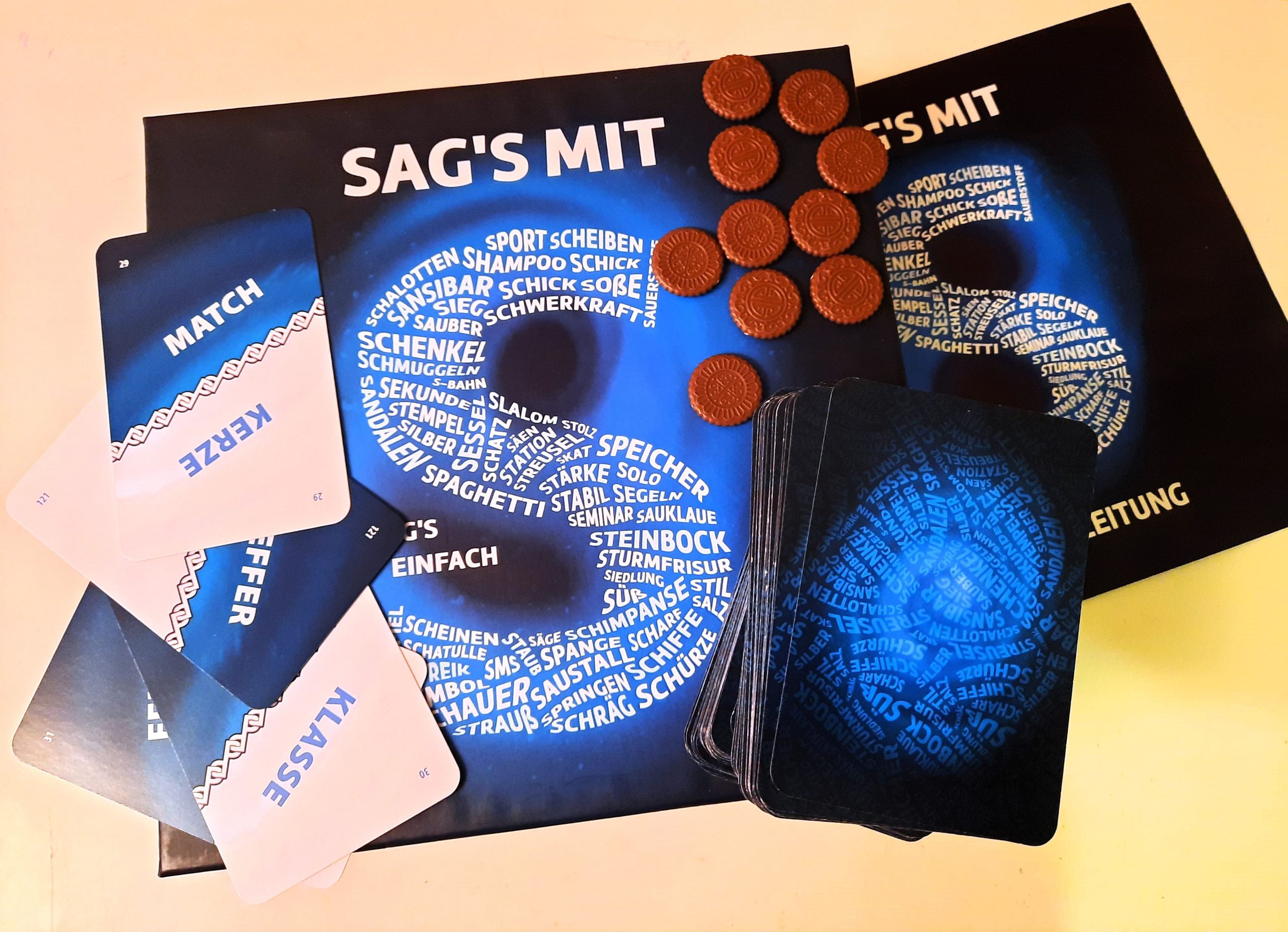 Man sieht die Spielepackung mit mehreren Karten, Schokotalern und einem Kartenstapel.