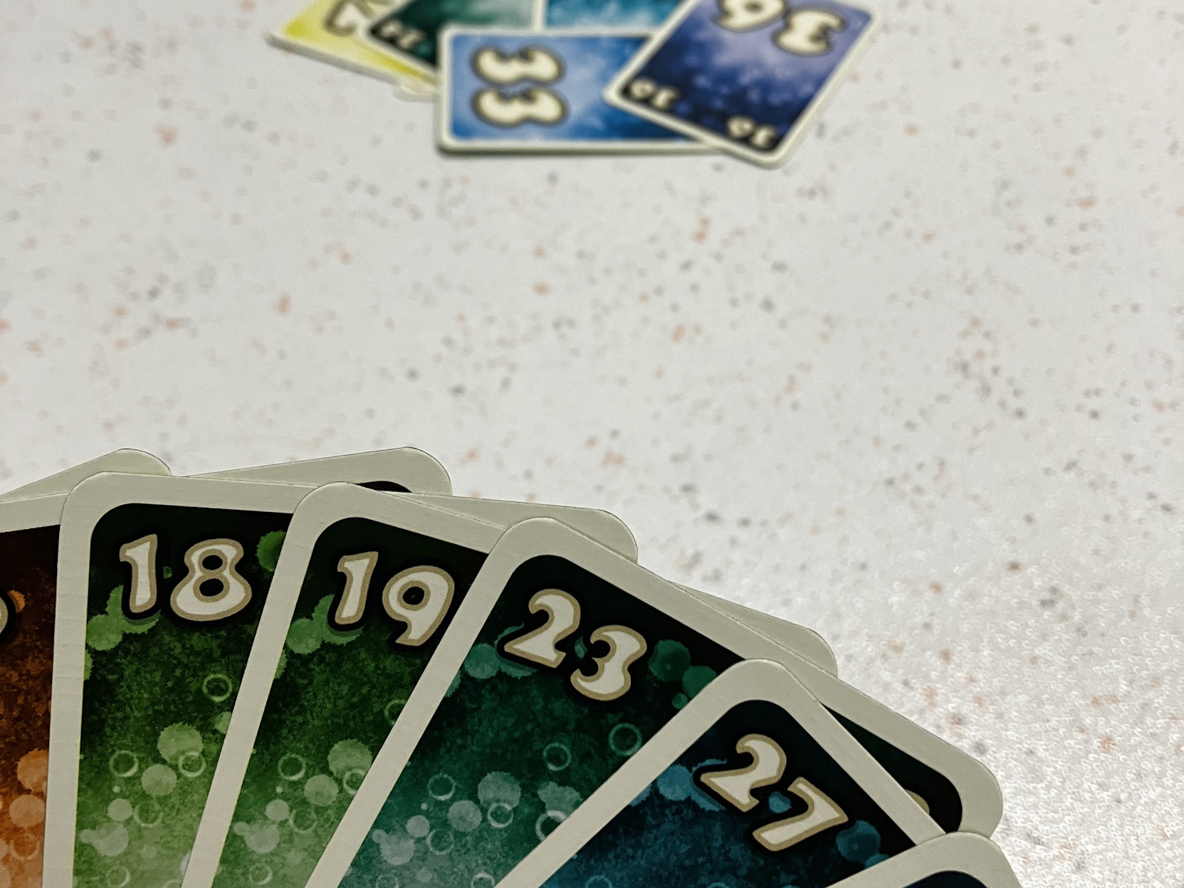 Szene aus dem Spiel - Blick in die Kartenhand, dahinter der Stapel gespielter Karten.