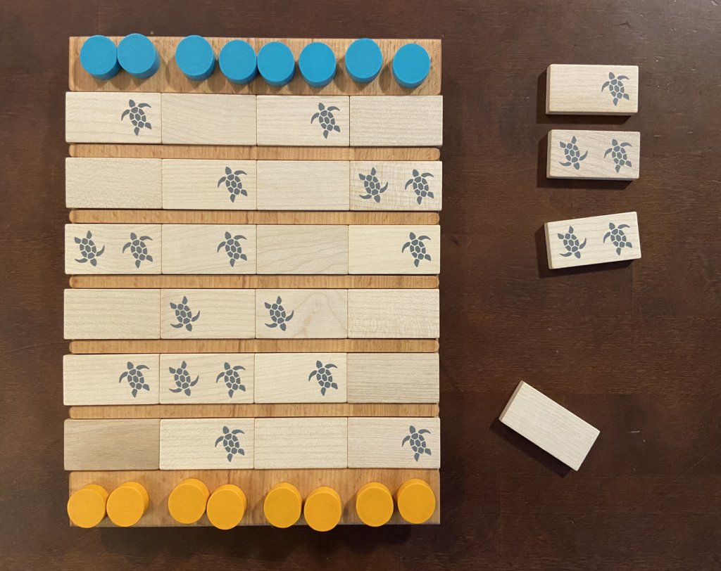Die Spielsteine liegen am Rand des Bretts. In den Rillen sind die Teile mit Schildkröten eingelegt.
