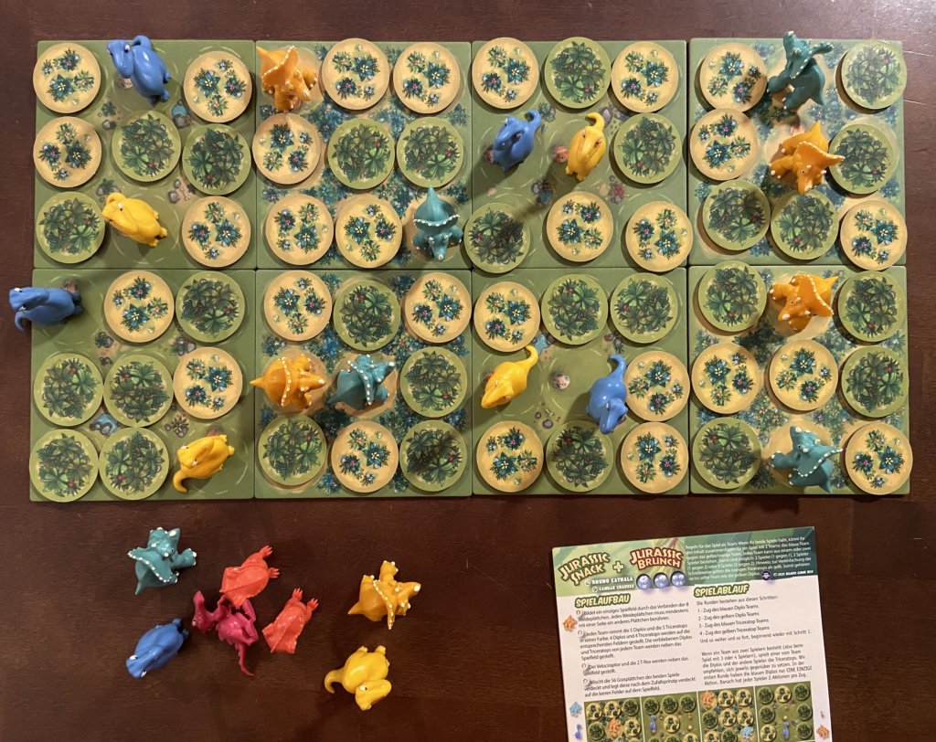 Aufbau der Kombination aus beiden Spielen, großes Spielfeld mit Grasplättchen und Dinos, daneben die weitern Figuren.