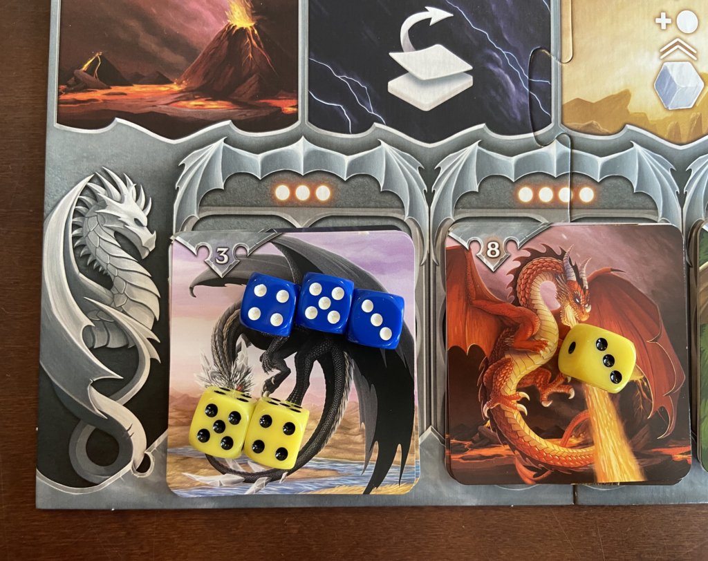 Auf einer Drachenkarte liegen 2 gelbe Würfel mit einem Wert von 9 und 3 blaue Würfel mit einem Gesamtwert von 12