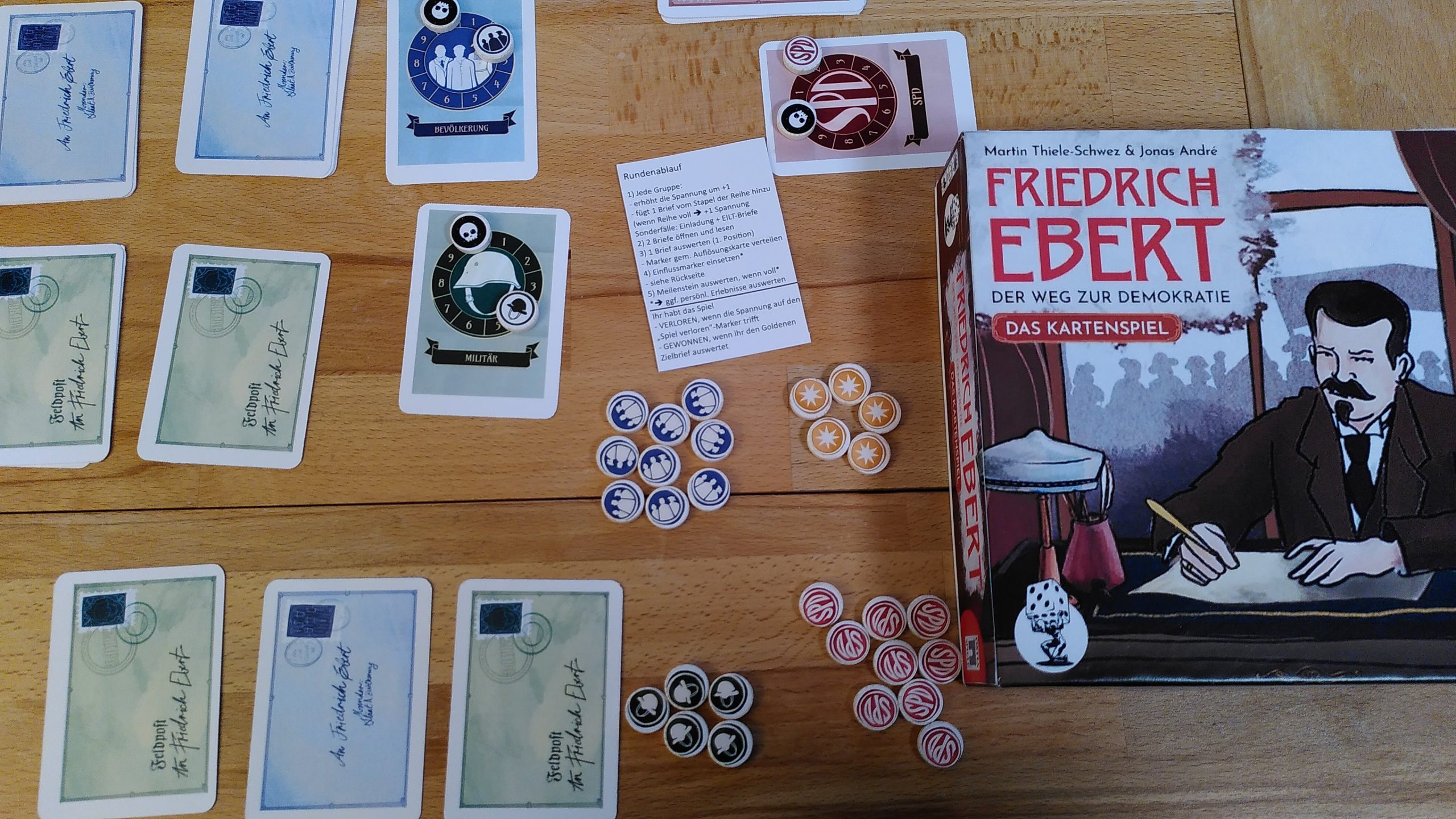 Überblick über einen Teil des Spielmaterials des Prototyps und die Spielschachtel. Das Material und ggf. auch die Grafik werden sich aber noch ändern.