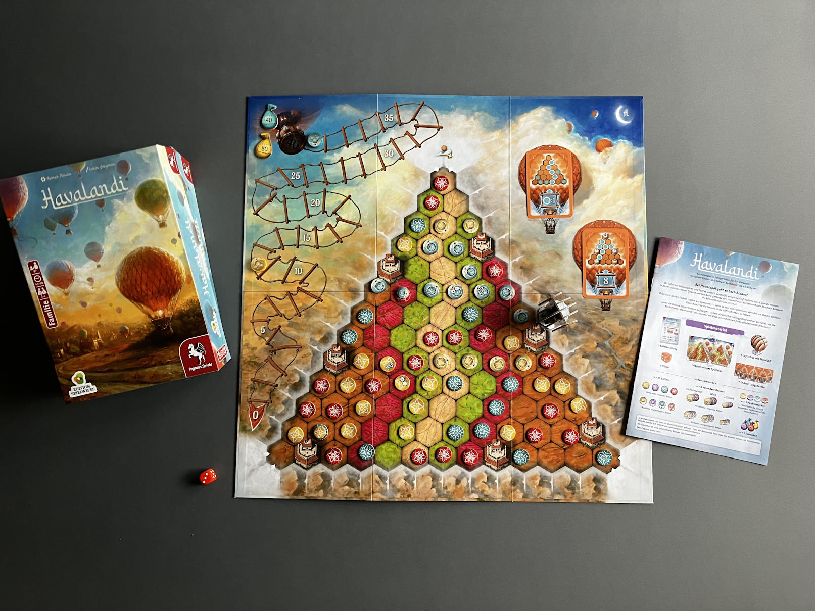 Übersicht über das Spielmaterial. Ein zentrales Spielbrett und dazu eine Menge Pappmarker, die darauf platziert werden.