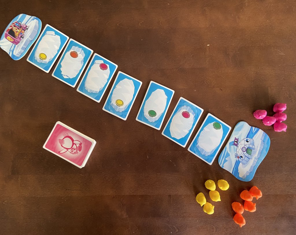 Eine Reihe Schollenkarten liegt aus, daneben der Nachziehstapel und am Start die Pinguinfiguren.