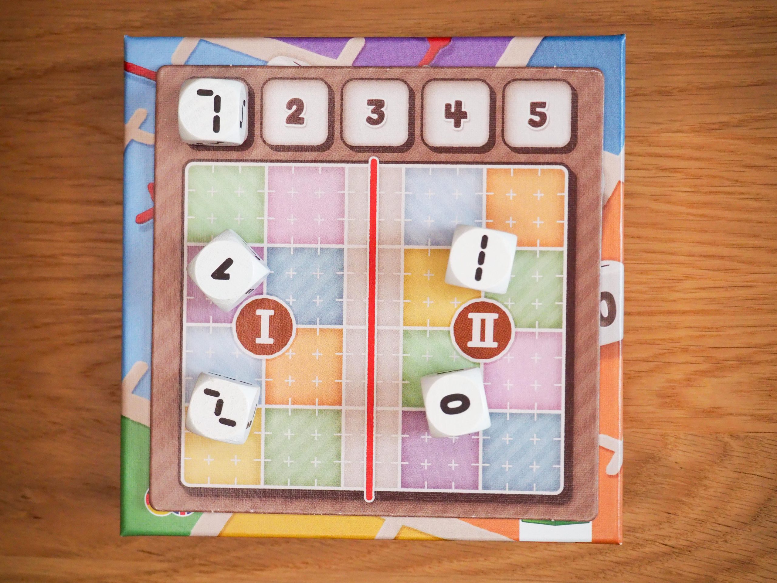 Würfelablage mit Rundenanzeige von 1 bis 5 in der oberen Reihe mit einem Würfel liegend auf der 1. Linker und rechter Bereich beherbergen jeweils zwei Würfel und sind durch eine graue Zone und einen roten Strich getrennt.