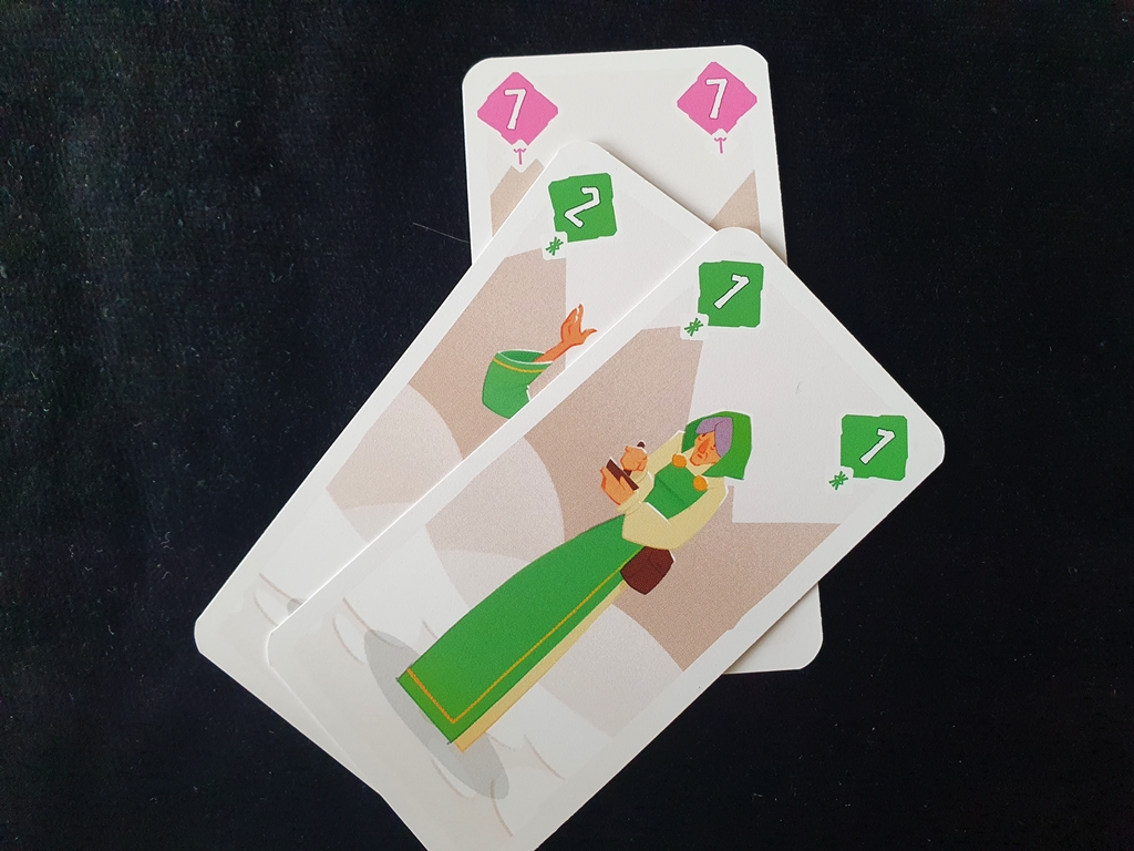 Zwei grüne Karten überstechen die ausliegende Karte.