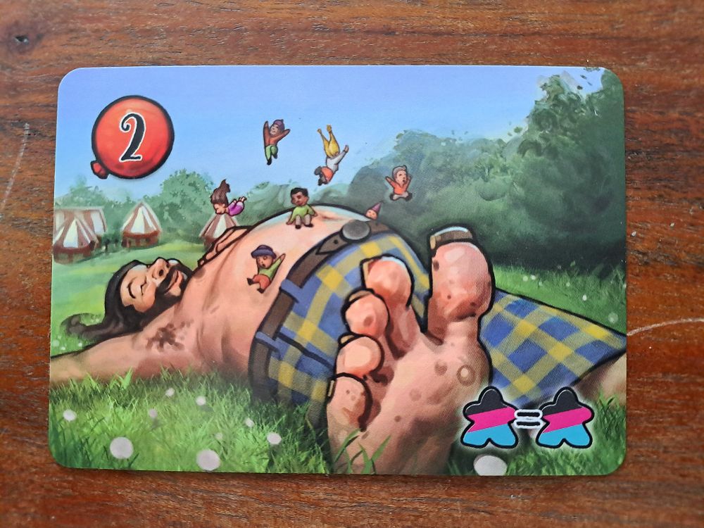 Zu sehen ist eine Attraktionskarte mit einem Riesen dessen Bauch als Trampolin dient.