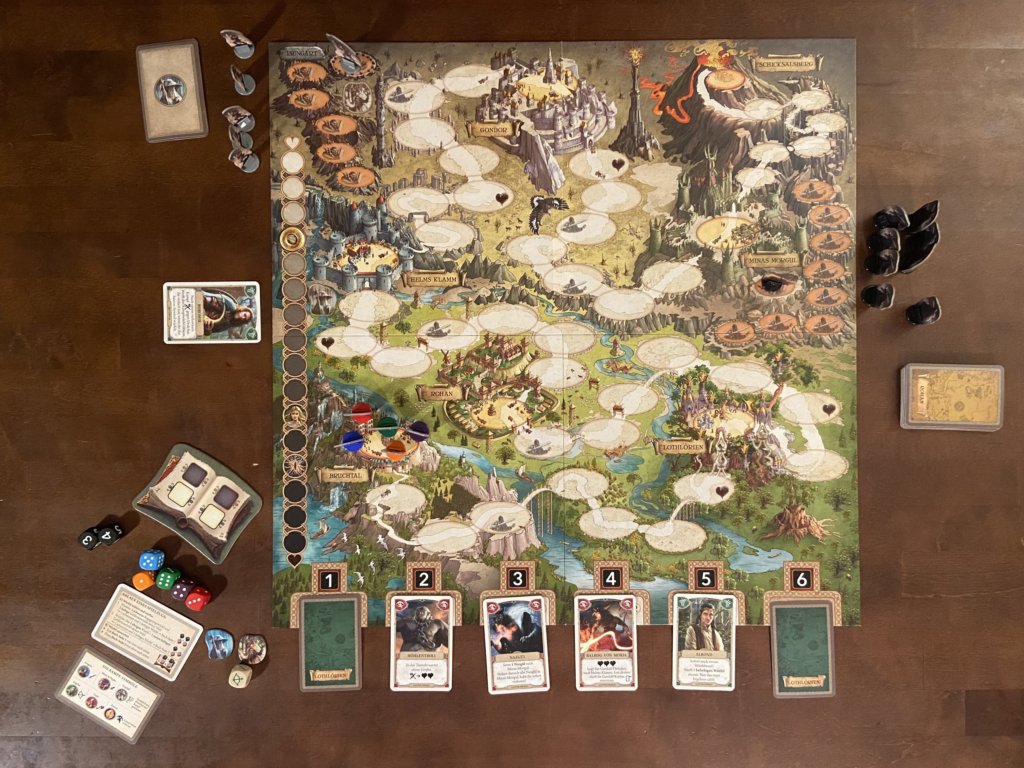Das Spielbrett liegt aus und im unteren Bereich 6 Karten, daneben Würfel und weiter Figuren