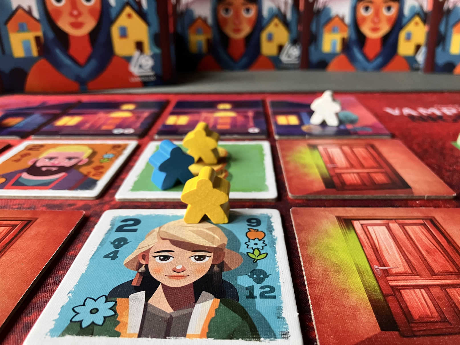 Detailaufnahme des Spiels. Drei Spielfiguren stehen hintereinander auf Spielkarten.