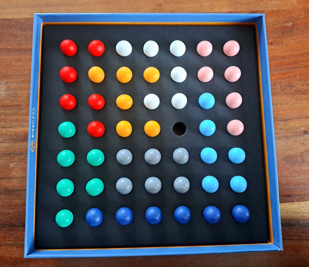 Blick in die Spielschachtel am Spielende. Alle Murmeln sind nach Farbe sortiert.