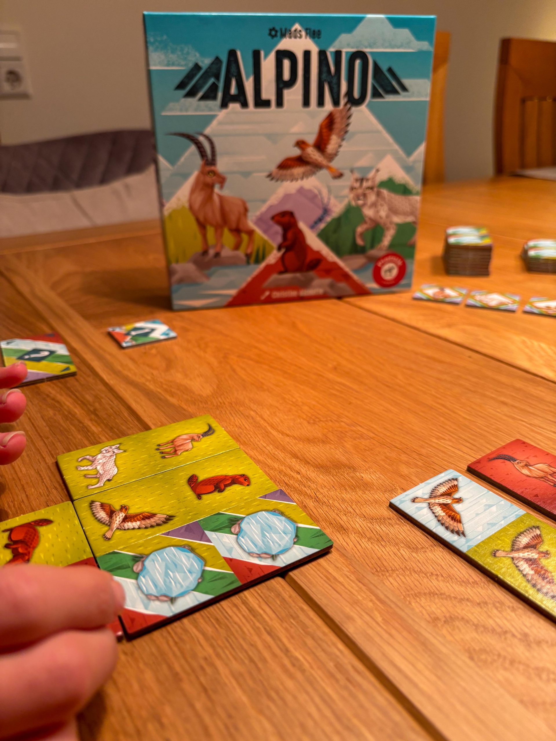 Spielschachtel unscharf im Hintergrund. Im Vordergrund angelegte Landschaftsplättchen.