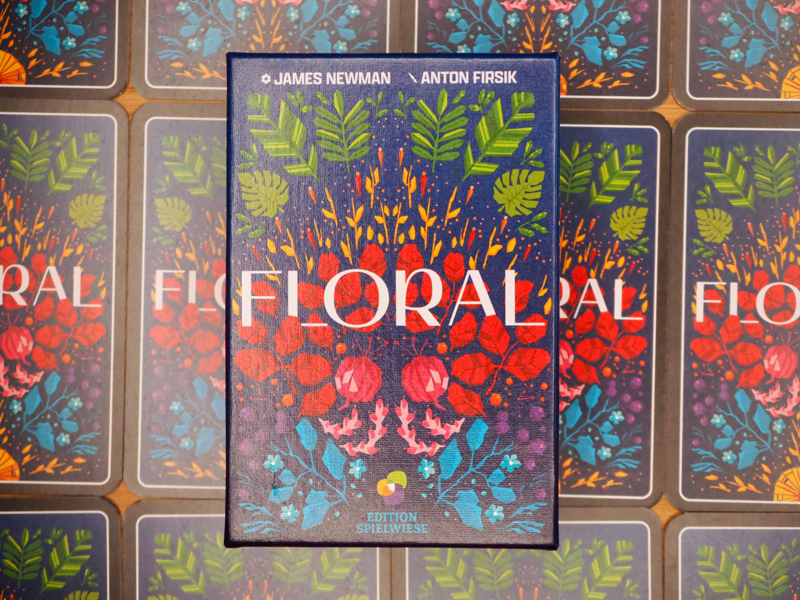 Spielschachtel mittig auf einem Raster aus Karten mit dem gleichen Cover wie die Schachtel selbst. Weißer Schriftzug mittig auf buntem Blumenhintergrund