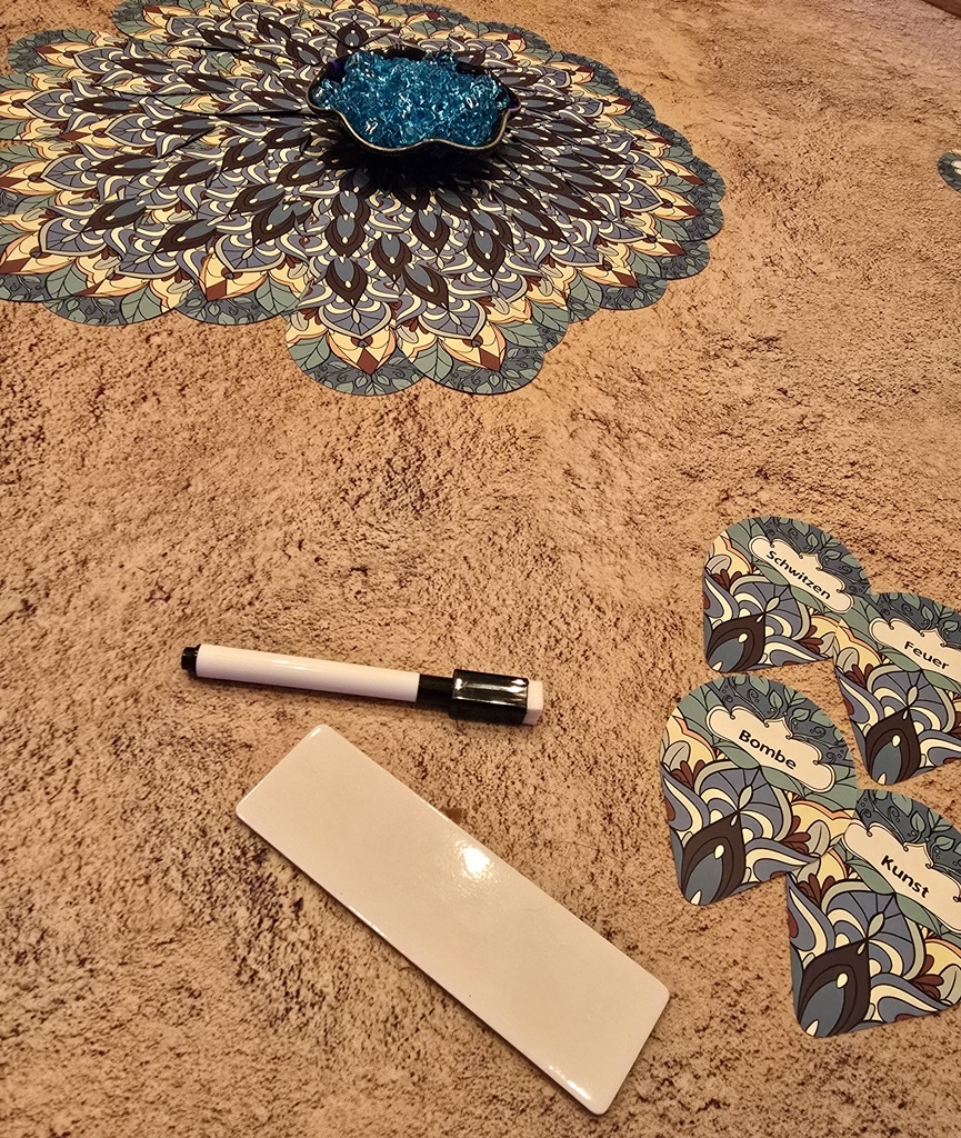 Das Pfauenrad in der Mitte des Tisches, einzelne Wortkarten, Stift und Beschriftungsschild.