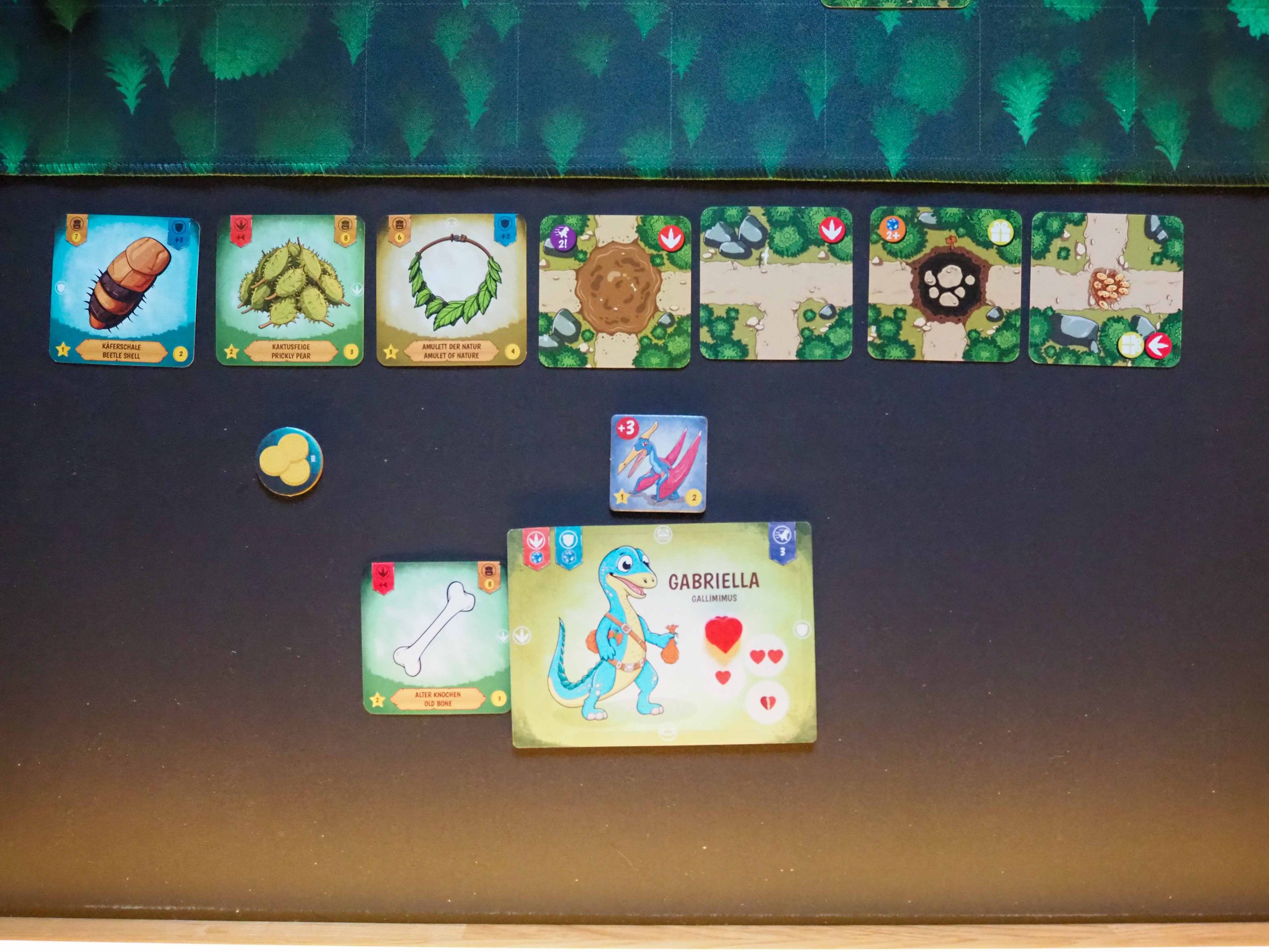 Bild der Auslage auf schwarzem Untergrund. Sieben quadratische Kacheln und darunter das Charaktertableau.