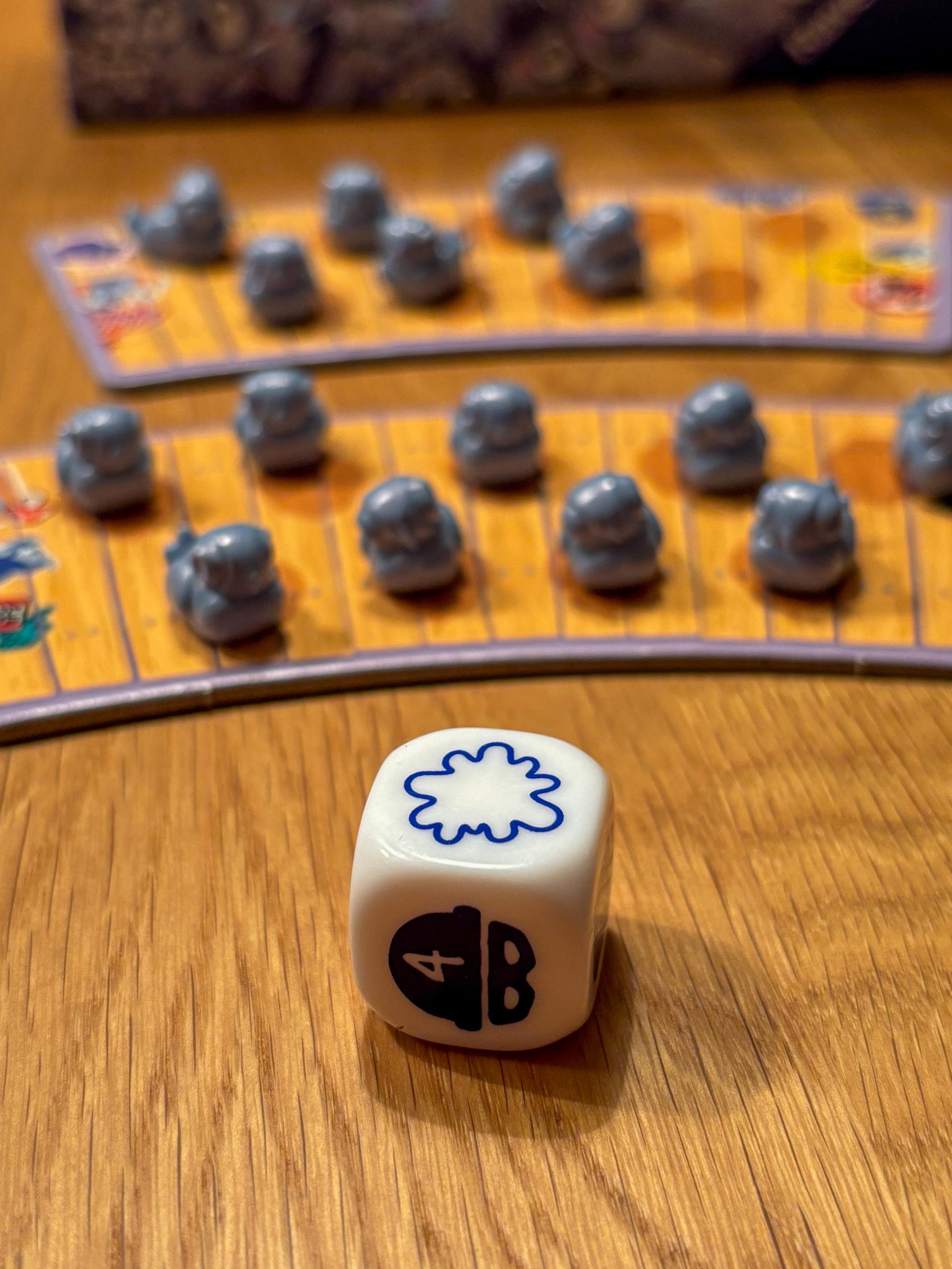 Weißer Würfel mit blauen Symbolen im Vordergrund. Im Hintergrund zwei Taubenbänke mit einigen der kleinen Tauben. 