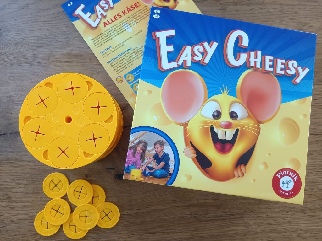 Auf dem Bild ist der Karton mit dem Inhalt zu sehen. Außer der Schachtel ist das Käse-Roulette, die Cheesy Ringe, sowie die Spielanleitung beinhaltet.