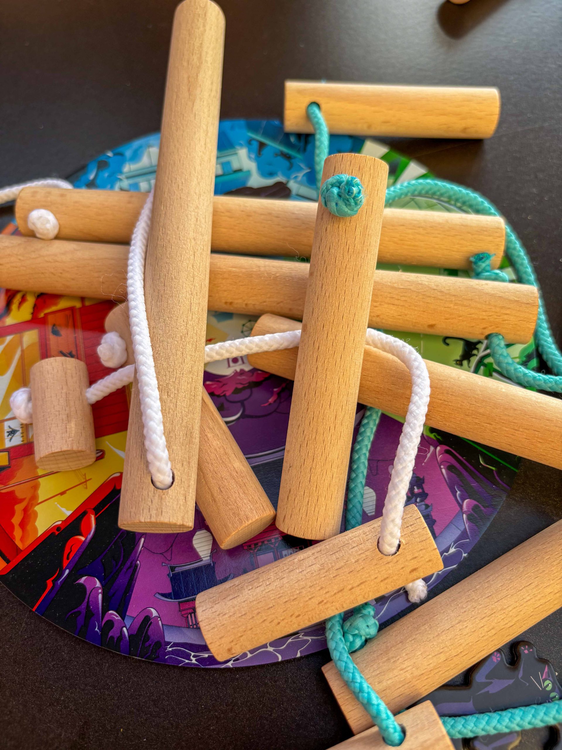 Durcheinander liegende Holzstäbe mit bunten Seilen.
