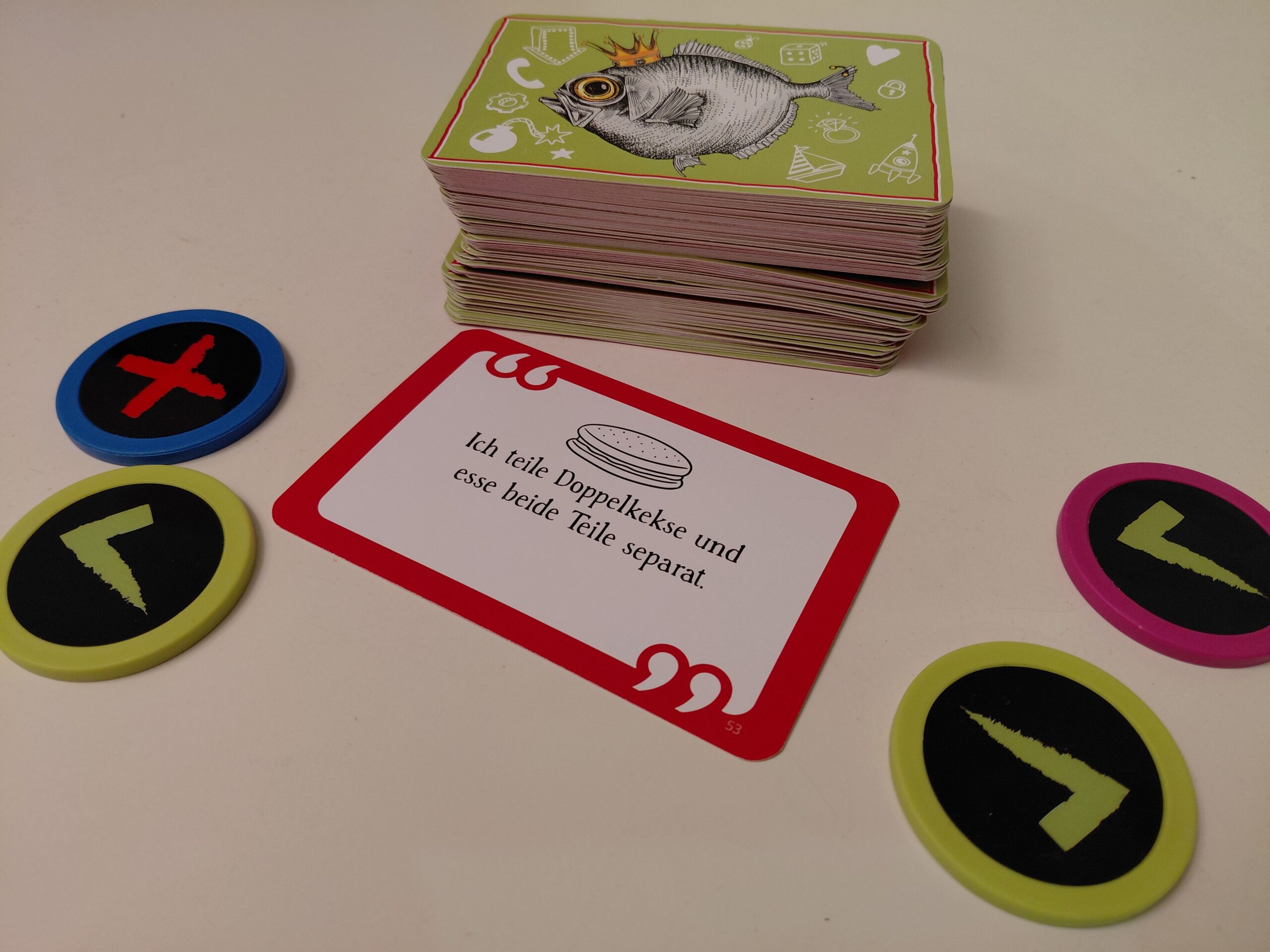 Ein verdeckter Kartenstapel, die Aufgabenkarte und die Einschätzungschips der Spieler liegen auf dem Tisch.