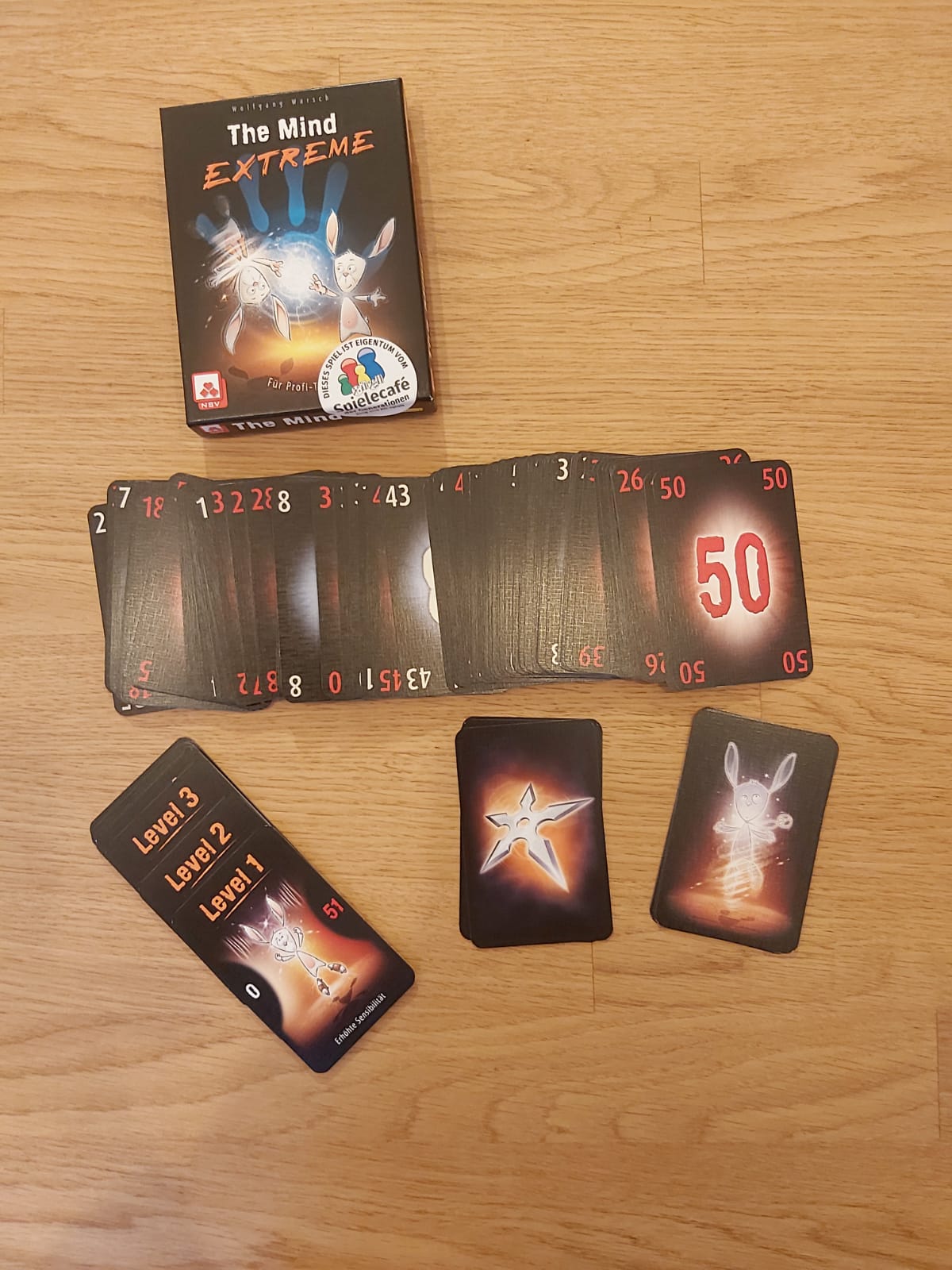 Zu sehen sind die Verpackung von The Mind Extreme sowie alle zum Spiel gehörenden Spielkarten.