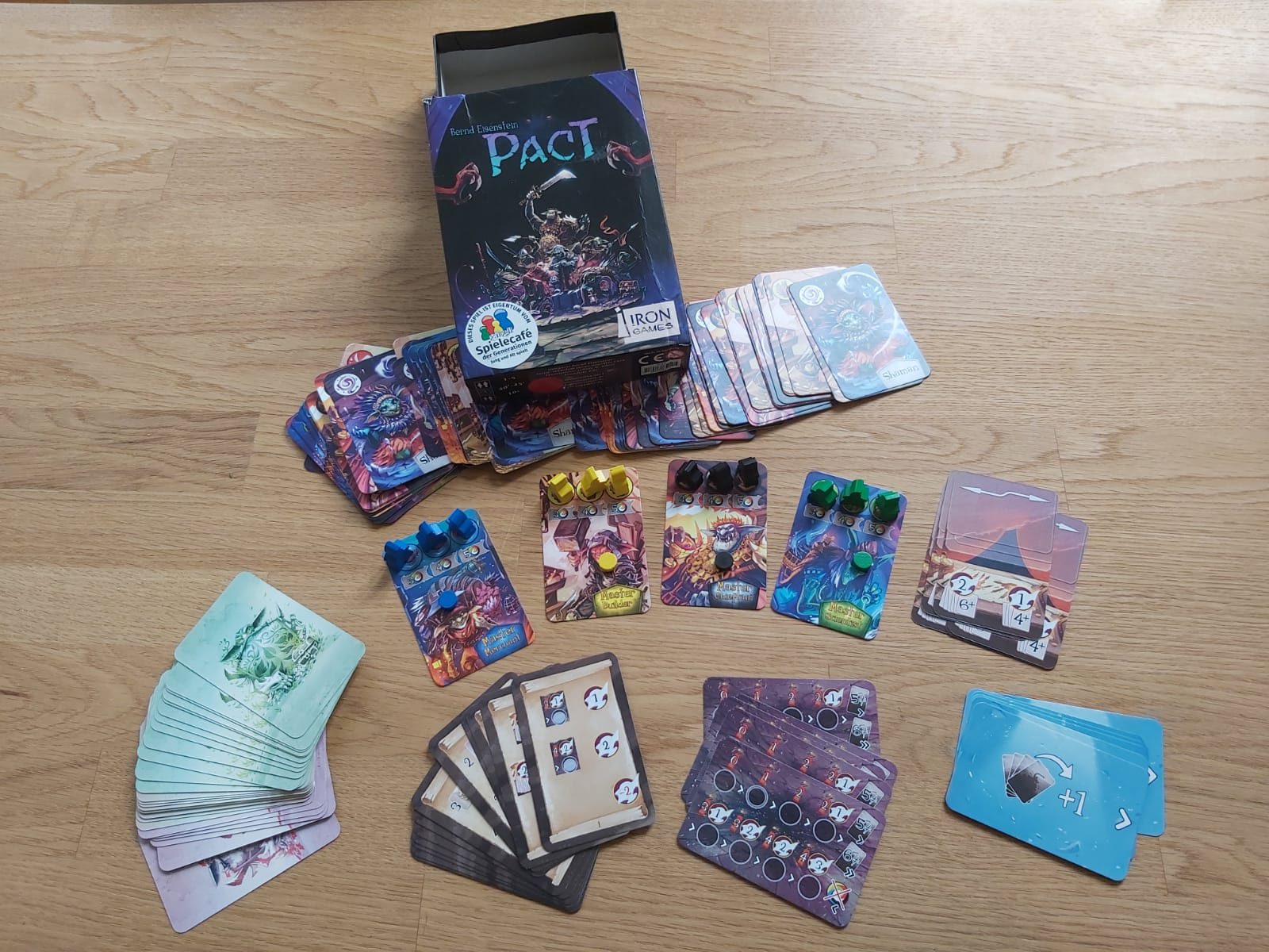Zu sehen ist die Spieleverpackung von "Pact" sowie das gesamte Spielmaterial.