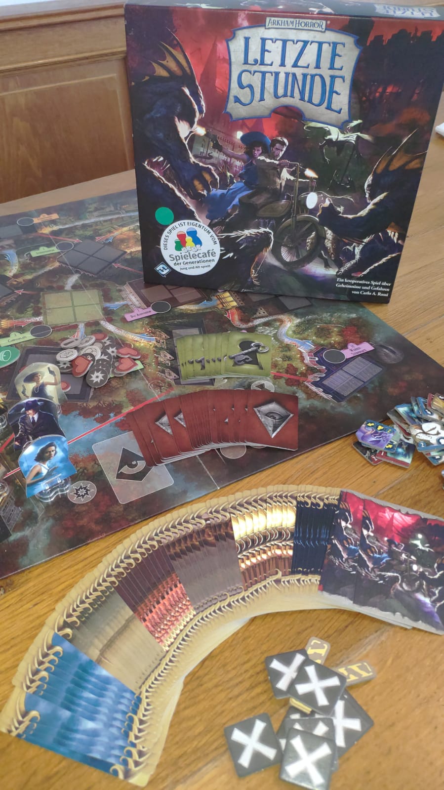 Zu sehen ist das Spiel Arkham Horror mit Spielverpackung & -material