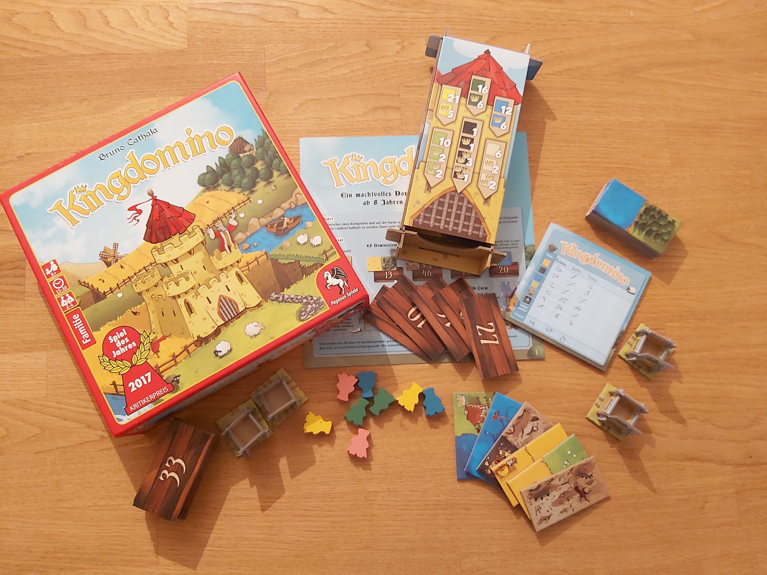 Zu sehen ist das Spiel Kingdomino mit dem gesamten Spielmaterial.