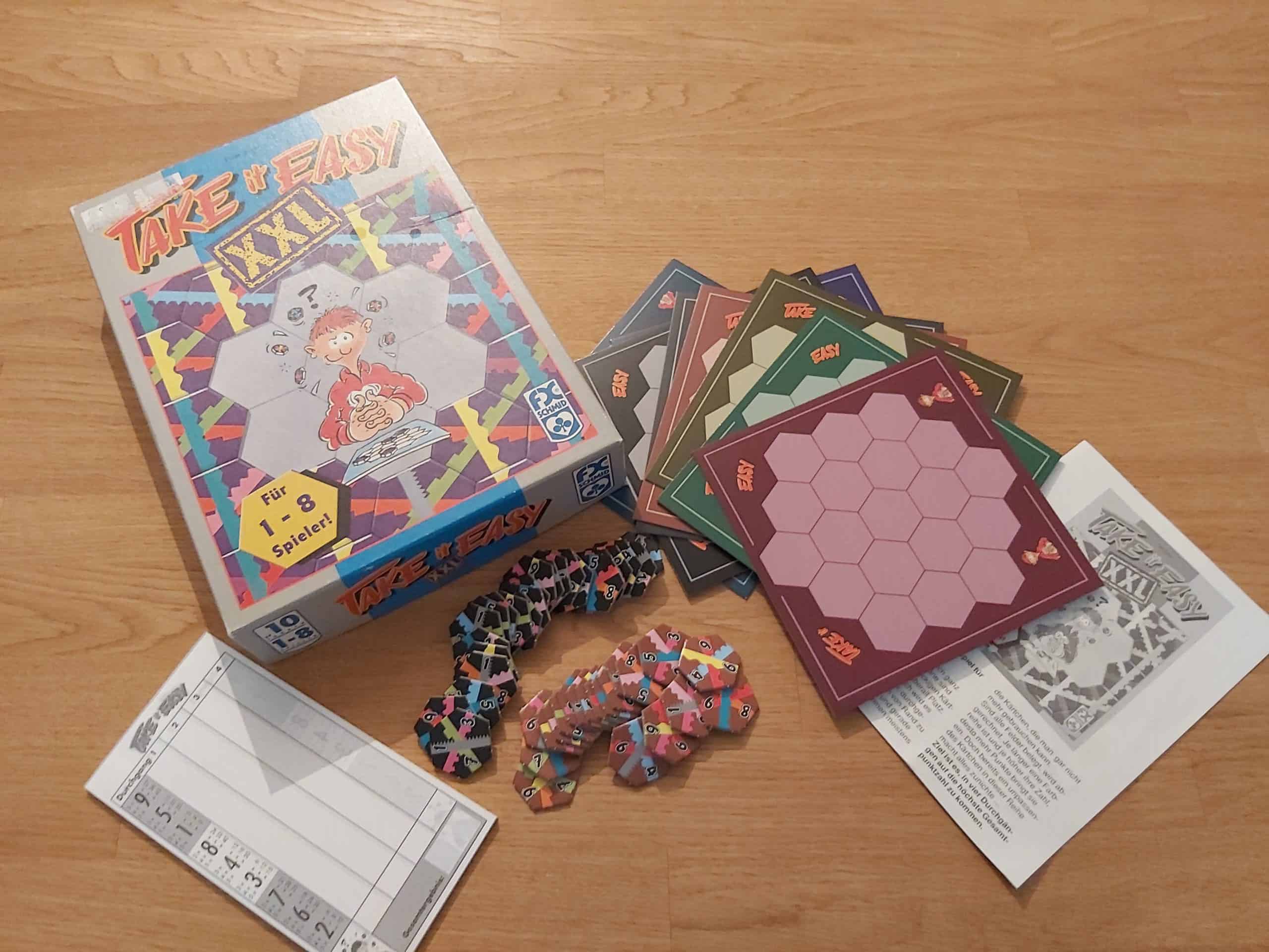 Zu sehen ist das Spiel Take it Easy XXL mit dem gesamten Spielmaterial.