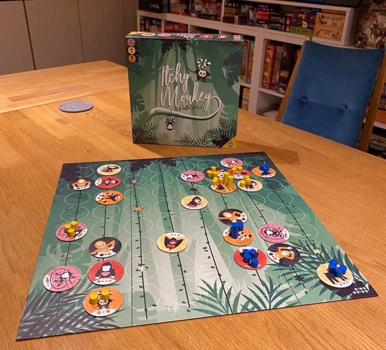 Zu sehen ist das Brettspiel Itchy Monkey mit dem gesamten Spielmaterial auf einem Holztisch.