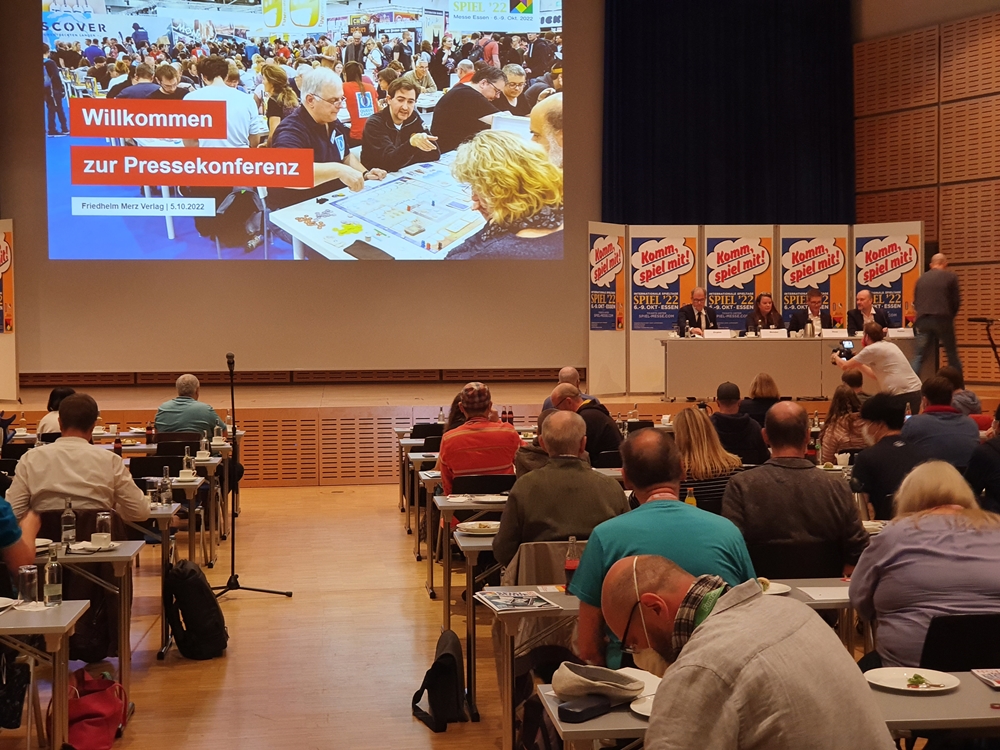 Festsaal mit Pressekonferenz. Es ist die Präsentation zu sehen und das Podium der Redner