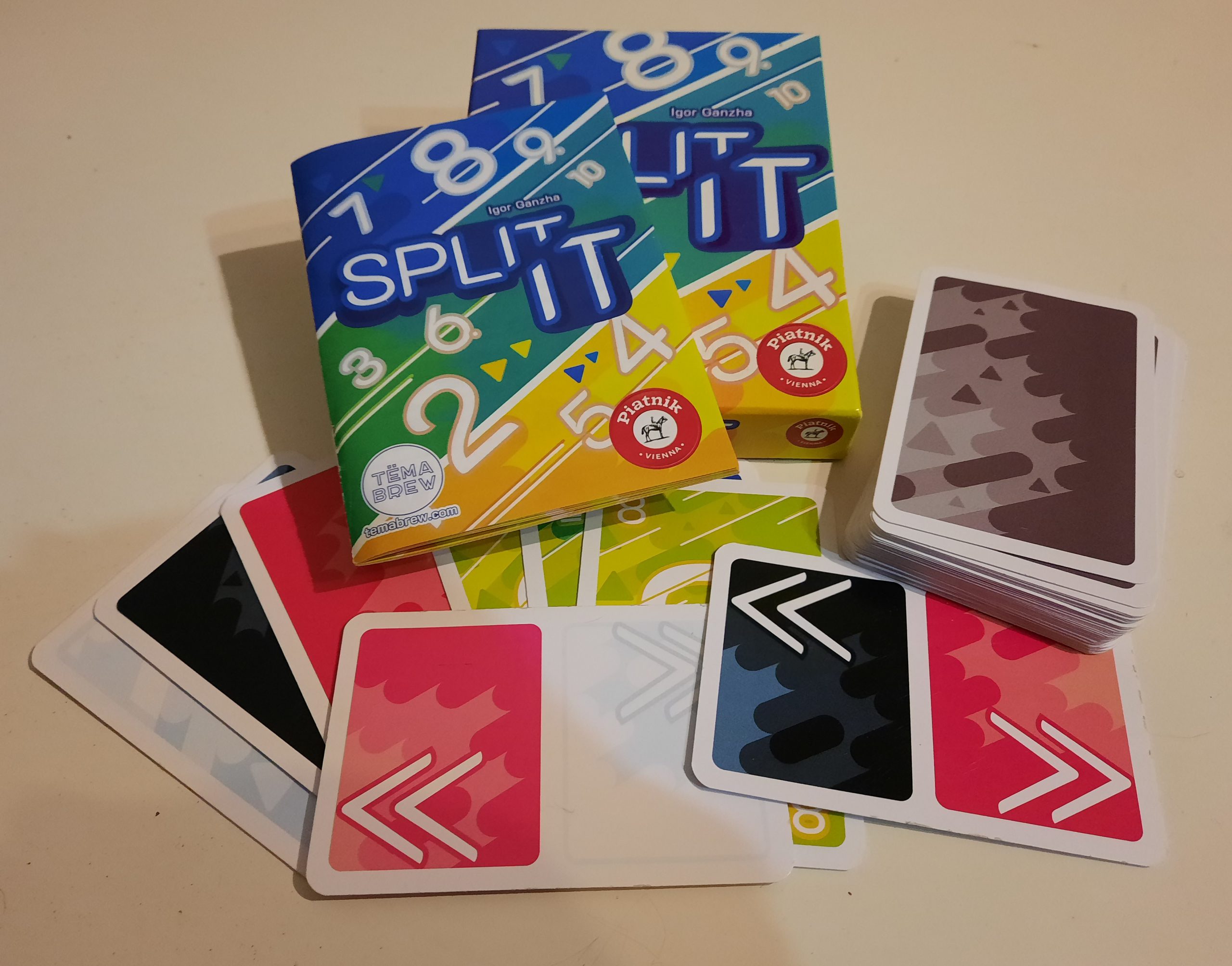 Auf dem Tisch liegen die Verpackung, die Beschreibung, ein Kartenstapel und mehrere Karten aufgefächert.