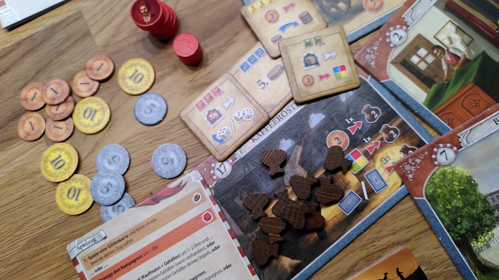 Ein kleiner Überblick über das Spielmaterial, bunte Orte, Münzen und Spielmaterial aus Holz