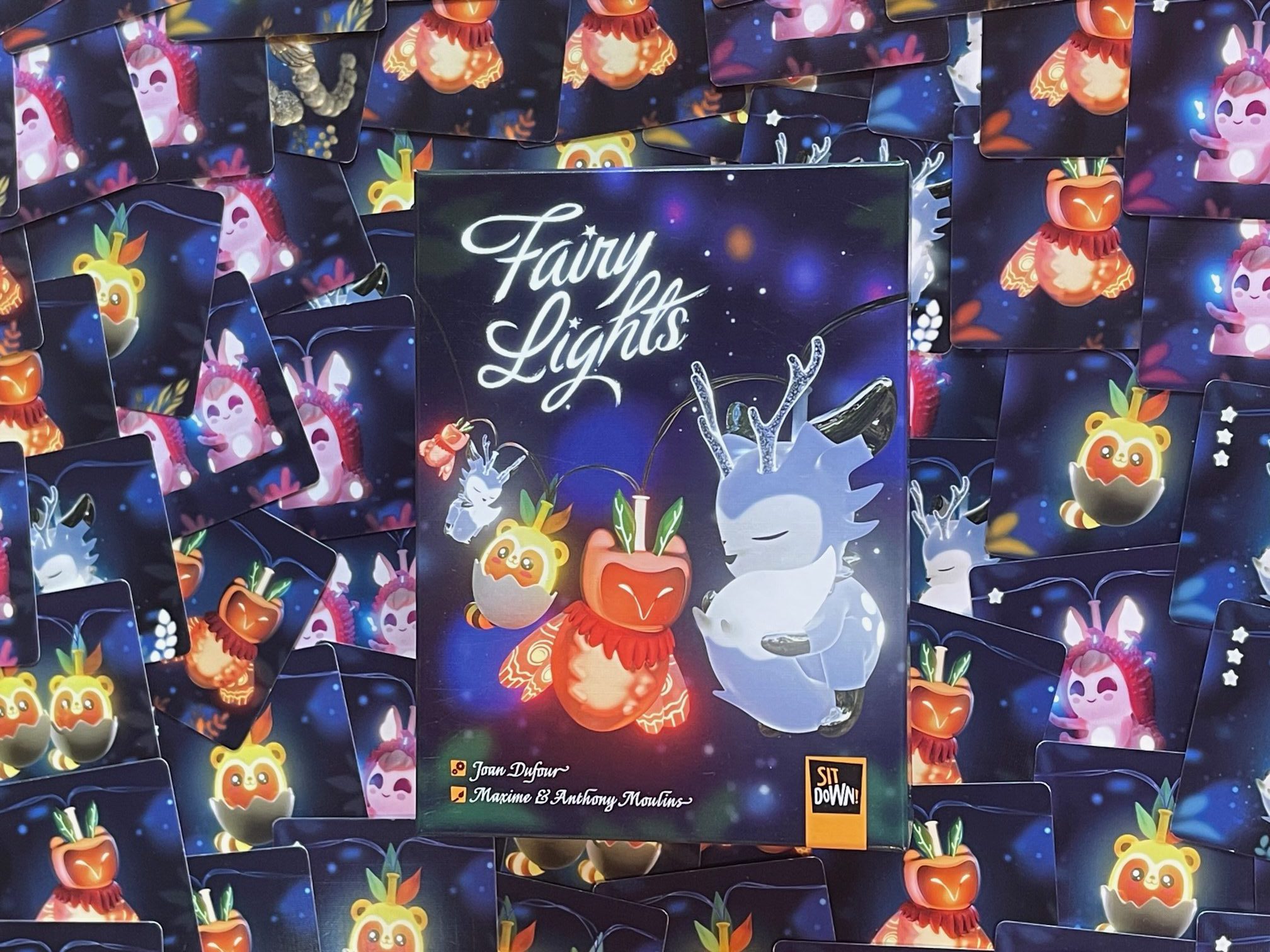 Auf dem Bild ist die Spielbox abgebildet. Die Spielkarten des Spiels fungieren als Hintergrund.