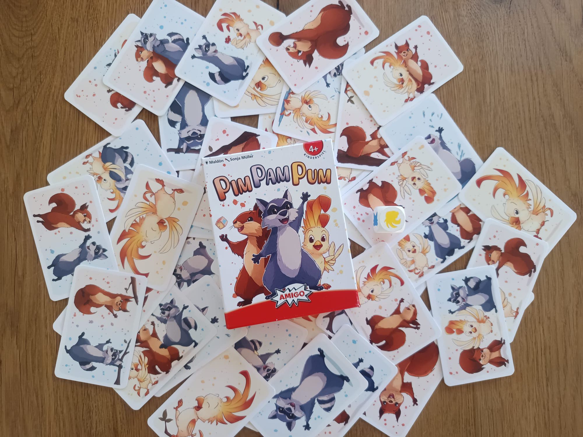 Auf dem Bild sind die Karten, der Würfel und die Schachtel zu sehen.